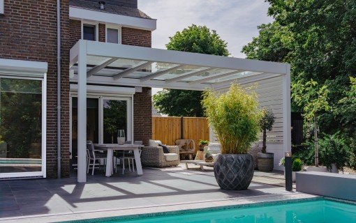 Weiße Aluminium-Pergola mit Glasdach auf einer Terrasse neben einem Pool