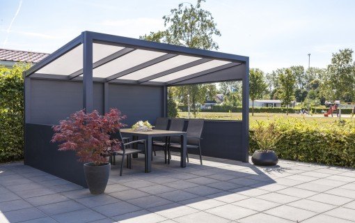 Anthrazitfarbene Aluminium-Pergola mit Sitzgruppe auf einer gepflasterten Terrasse
